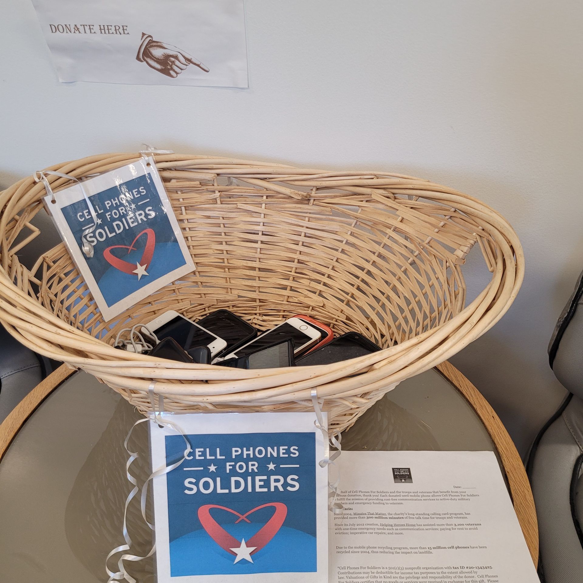 Basket of cell phones for soldiers, with signs, on a table. | Gainesville Garage & Trailer Sales