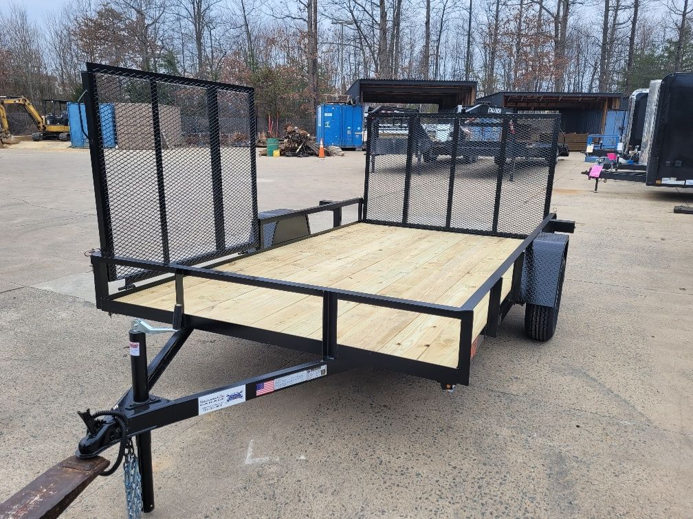 Black utility trailer with wooden deck, black mesh side rails, and hitch in an outdoor setting. | Gainesville Garage & Trailer Sales