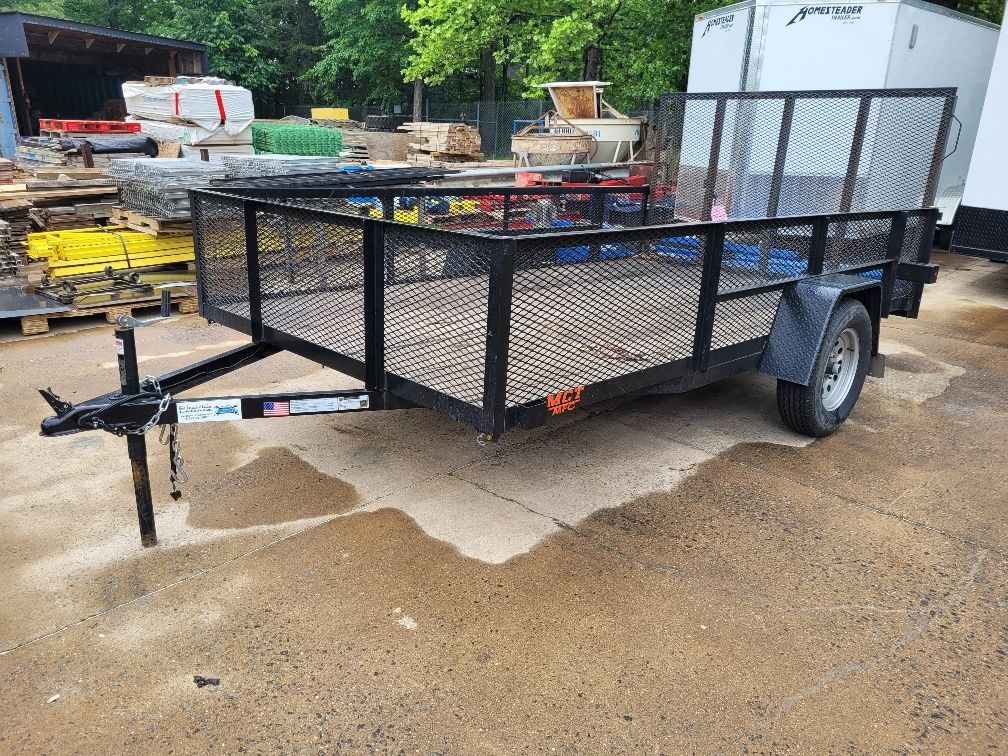 Black mesh utility trailer on a paved lot, various objects in the background. | Gainesville Garage & Trailer Sales