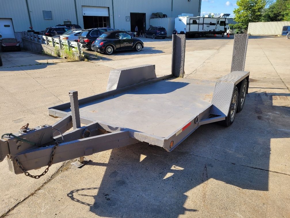 Gray flatbed trailer on a sunny day, parked in front of a building. | Gainesville Garage & Trailer Sales