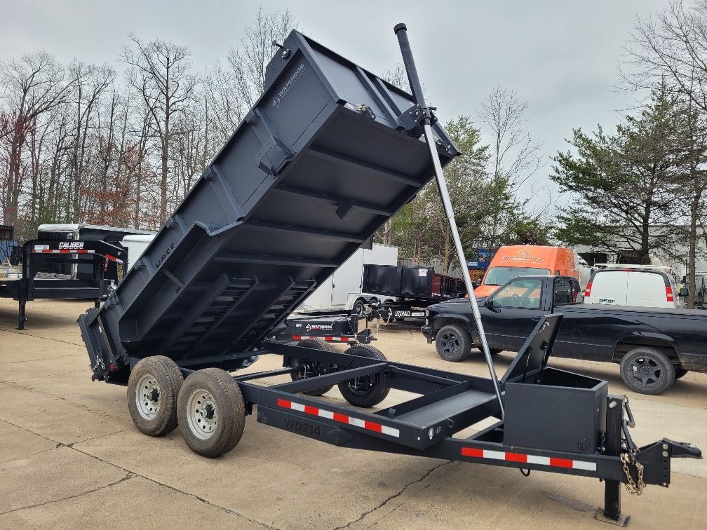 Black trailer with raised bed, on a paved lot. | Gainesville Garage & Trailer Sales