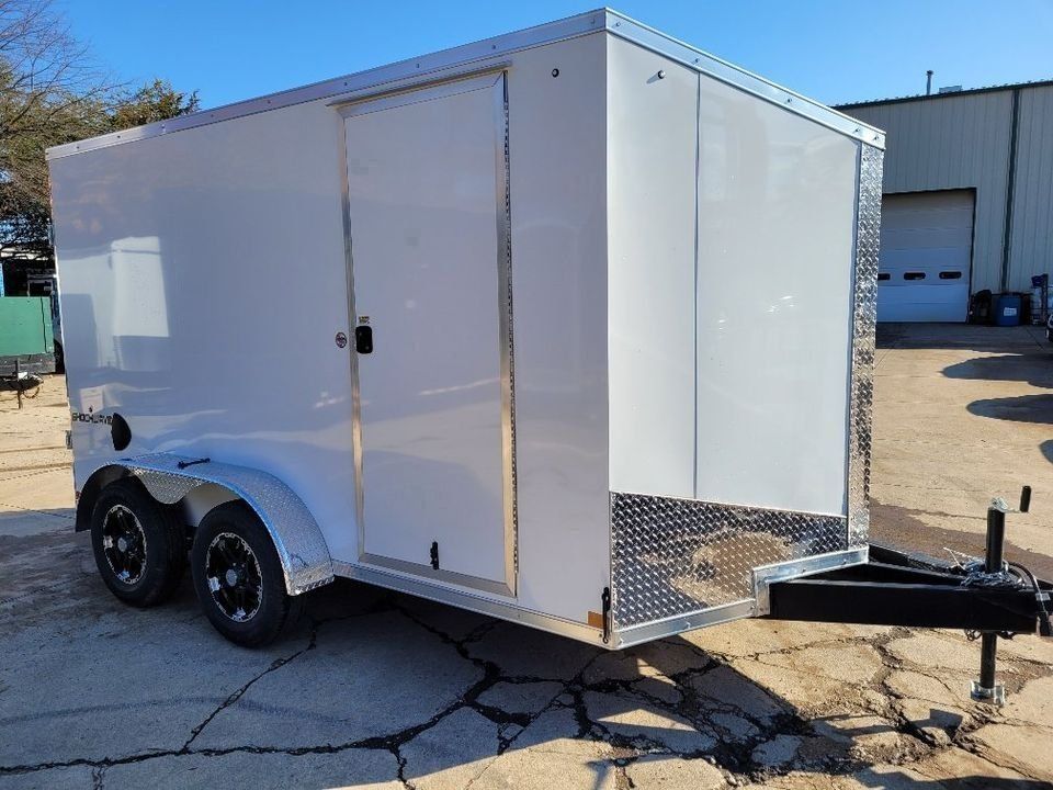 White cargo trailer with black wheels, on cracked pavement. | Gainesville Garage & Trailer Sales