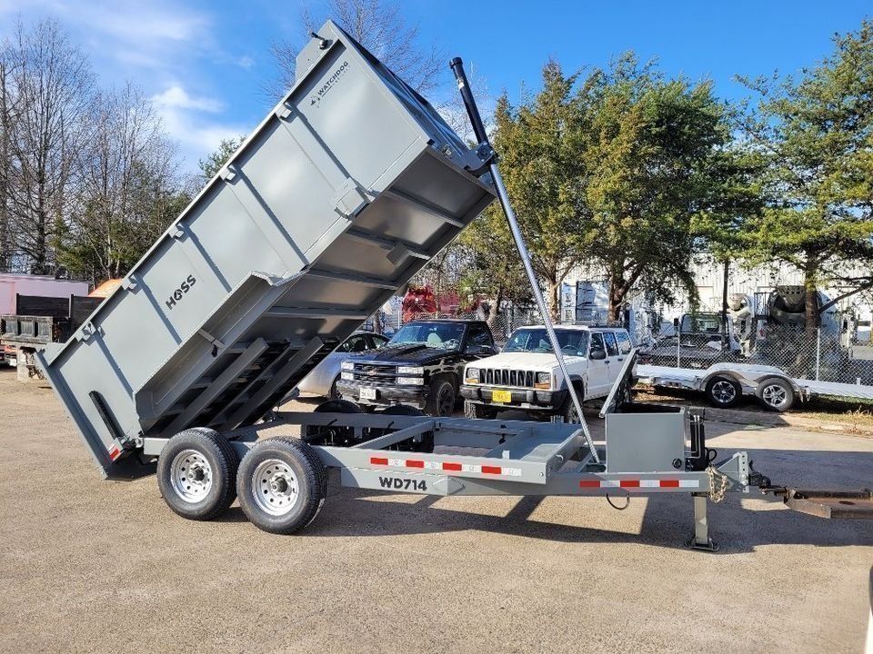 Gray dump trailer with raised bed, parked outdoors. | Gainesville Garage & Trailer Sales