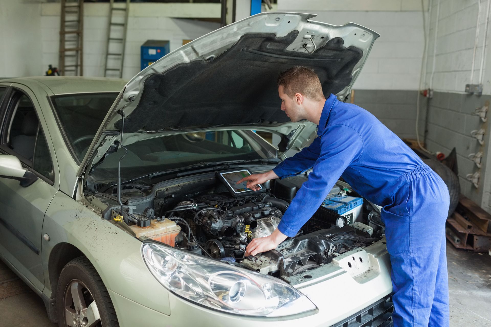 A man is working on the engine of a car in a garage.