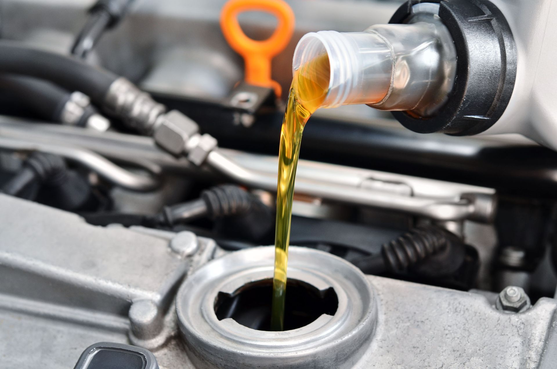 A person is pouring oil into a car engine.