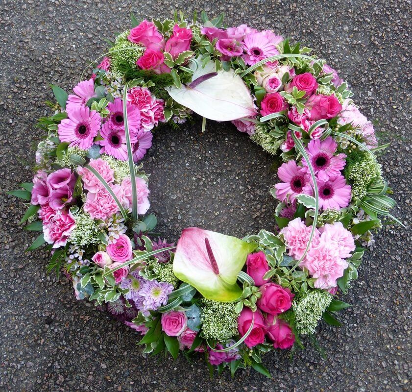36.  14” traditional wreath with Anthuriums, Roses, Germinis, Lisianthus and Carnations