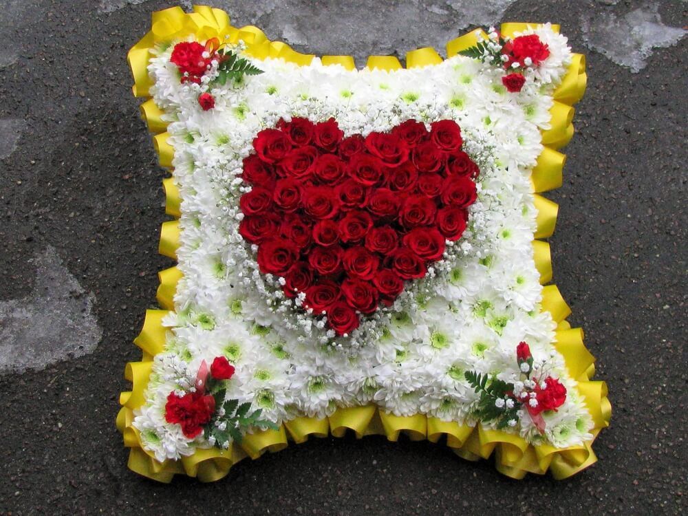 3. 18” Cushion with yellow ribbon edge, heart of red Roses to the centre with red Dianthus posies in each corner