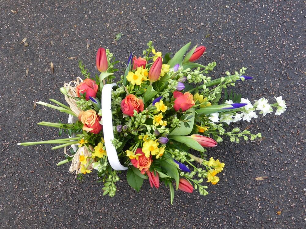 1.  Trug Basket with Cherry Brandy Roses, Blue Iris, White Larkspur, Red Tulips, Yellow Narcissus and lilac Freesias
