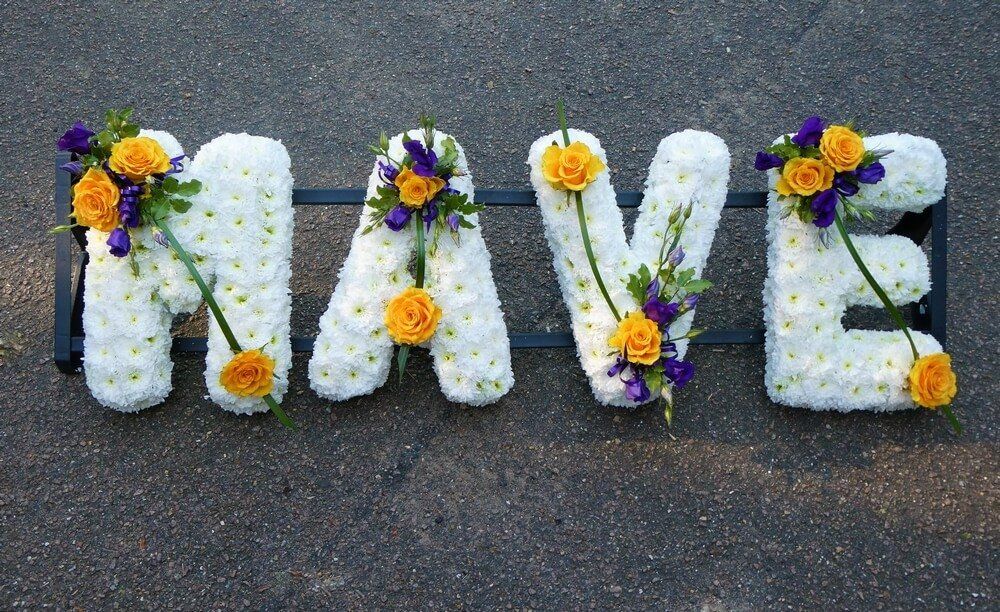 19. White letters clipped, posies of yellow Roses and purple Lisianthus