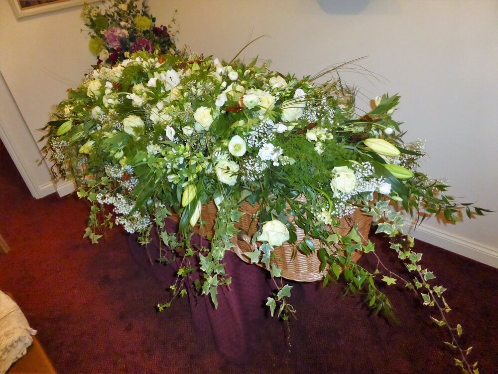 27. Very full coffin spray with white  Roses, Helebores, Alstromeria, Lilys, Lisianthus and trailing Ivy