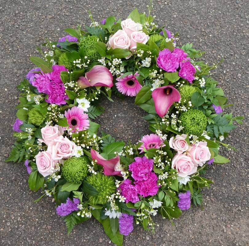 12.  16” traditional wreath with pink Callas, Germini, Roses, Carnations and green Bombellini Chrysanthemums