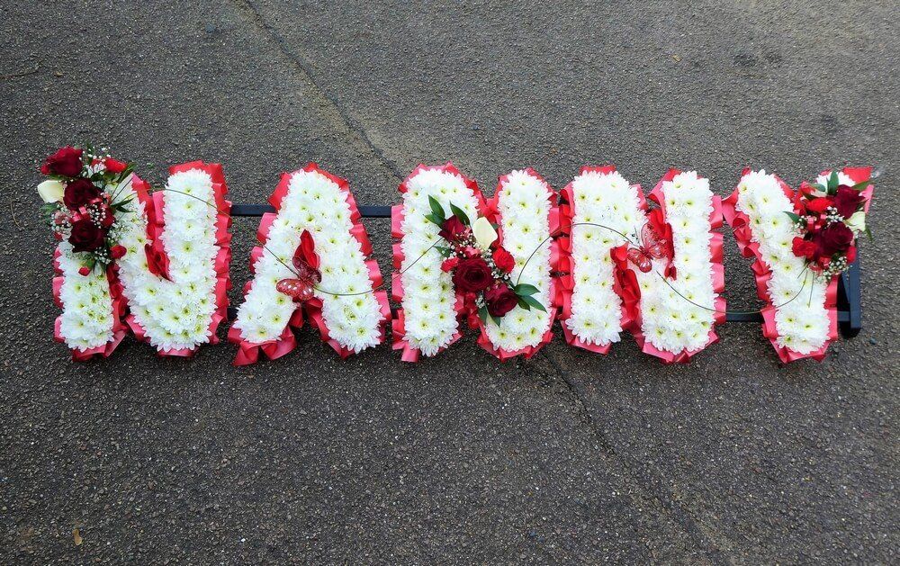 7.  NANNY with white letters, red Roses, white Callas and two red Butterflies