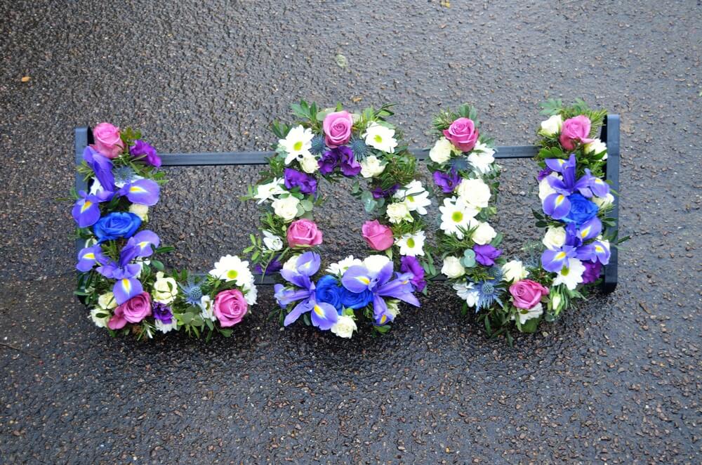 5.  Colourful letters with pink Roses, blue Delphiniums, Thistles, Roses, purple Lisianthus and white Chrysanthemums