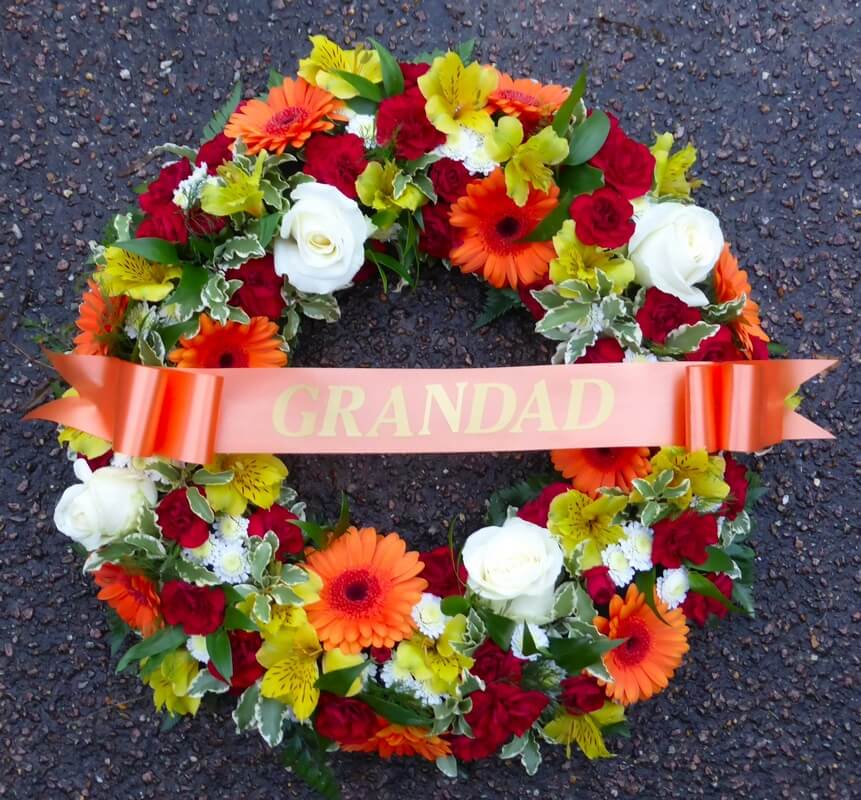34.   12” traditional orange, deep red, yellow and white wreath with ribbon sash