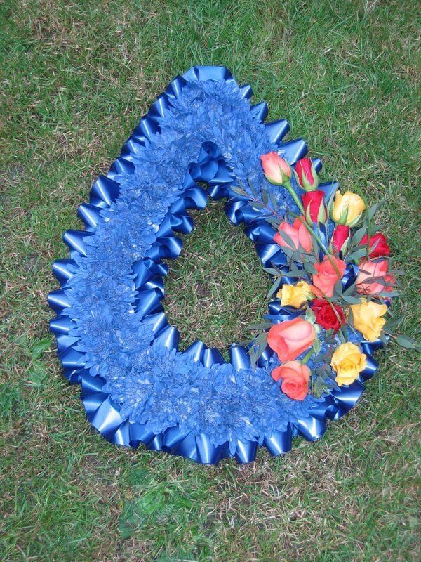 8. Teardrop with blue flowers with blue ribbon edge and posy of red orange and yellow Roses