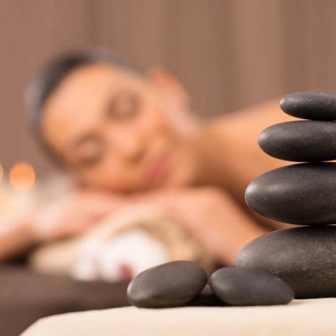 A woman is laying on a bed next to a pile of black rocks.