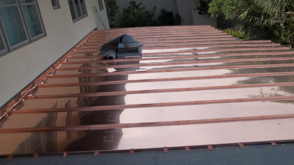 Copper roof panels being installed on a building, showing the new and shiny material.