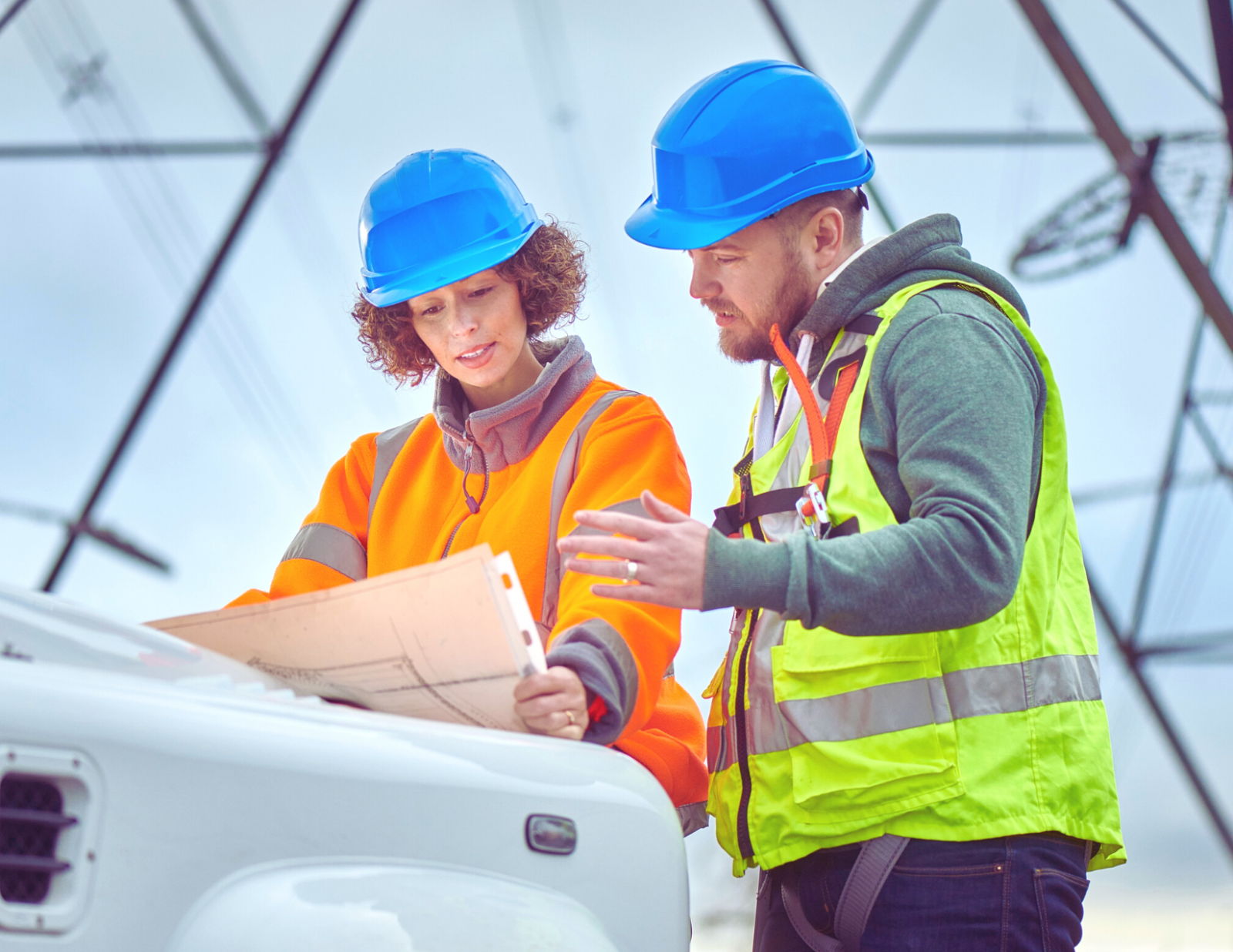 a man and a woman are standing next to a truck looking at a blueprint .