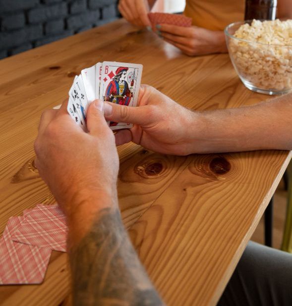 Um homem com uma tatuagem no braço está segurando um baralho de cartas-Pousada-Morada-dos-Passaros