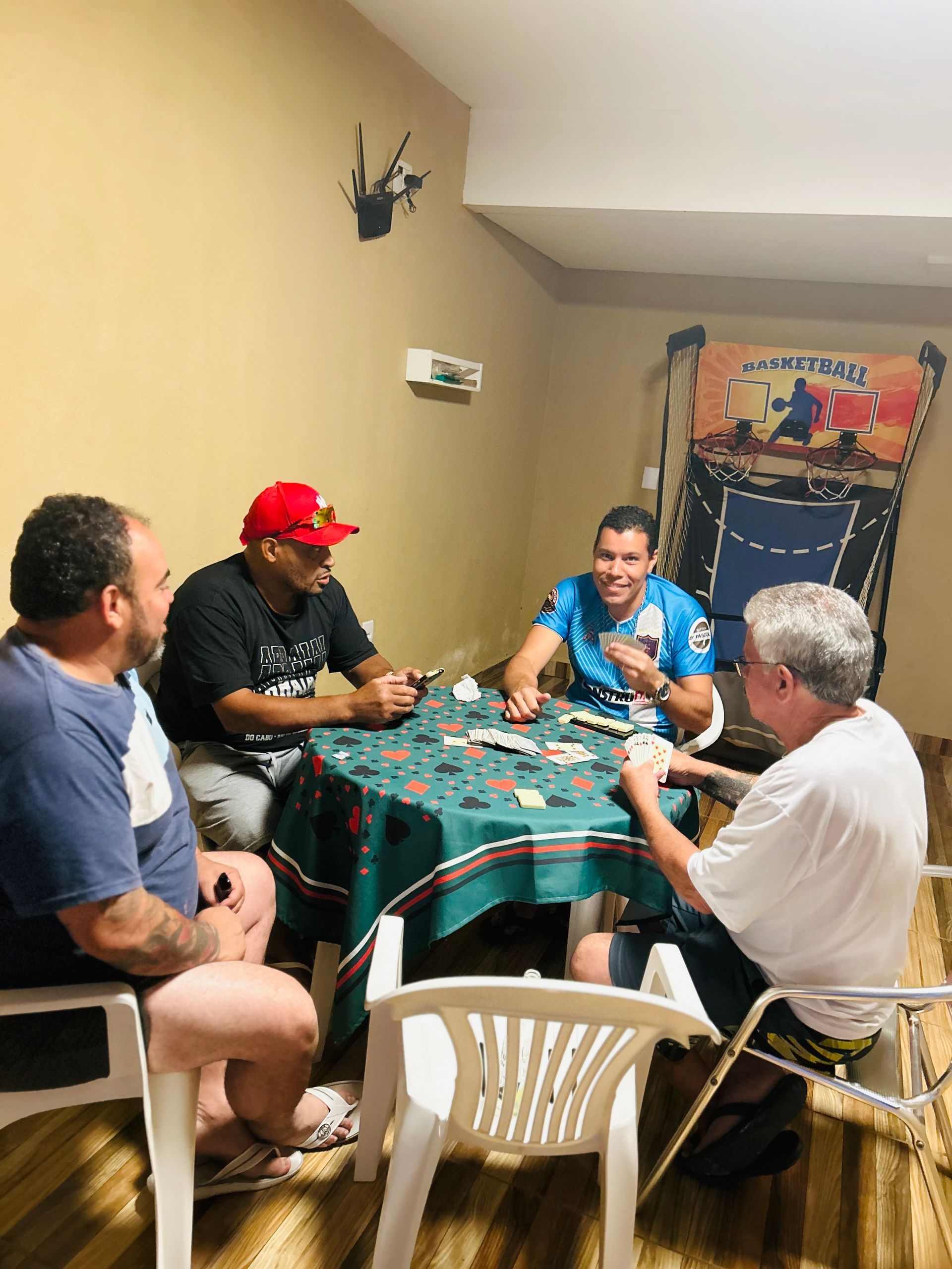 Um grupo de homens está sentado ao redor de uma mesa jogando cartas.-Pousada-Morada-dos-Passaros
