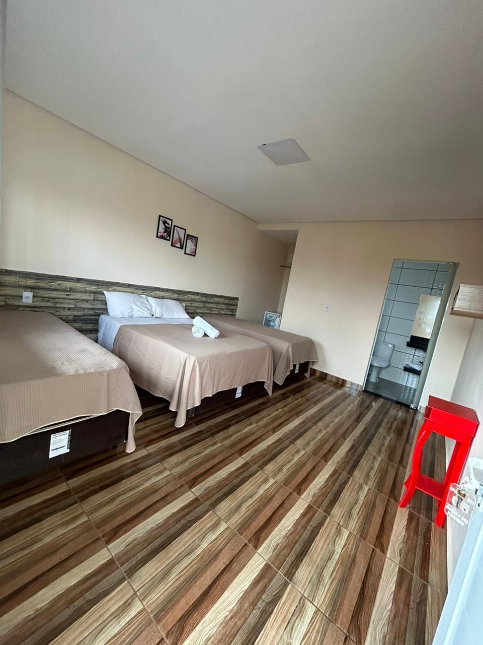 Um quarto de hotel com três camas e um banco vermelho.-Pousada-Morada-dos-Passaros