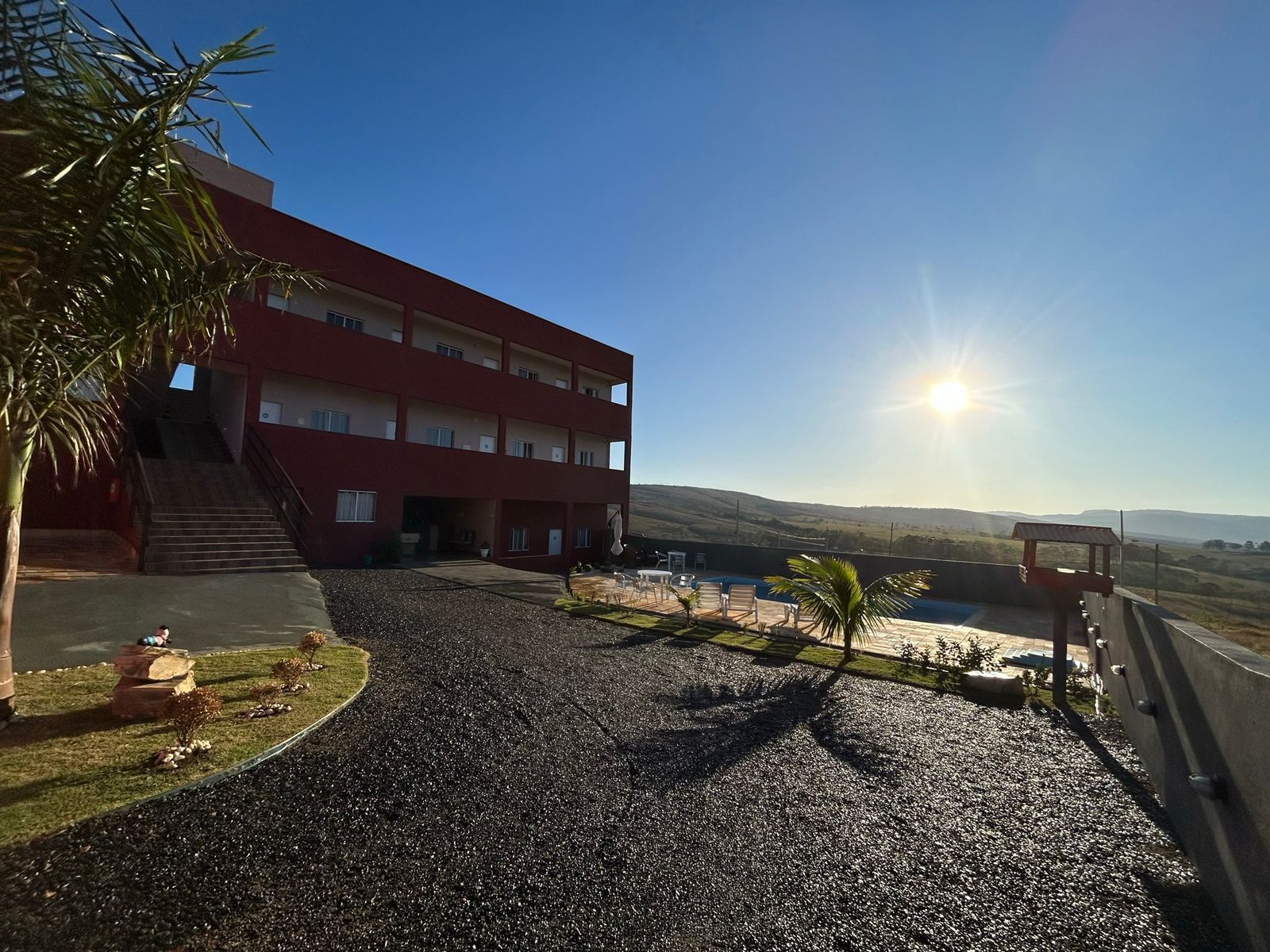 Um grande edifício vermelho com uma piscina na frente.-Pousada-Morada-dos-Passaros