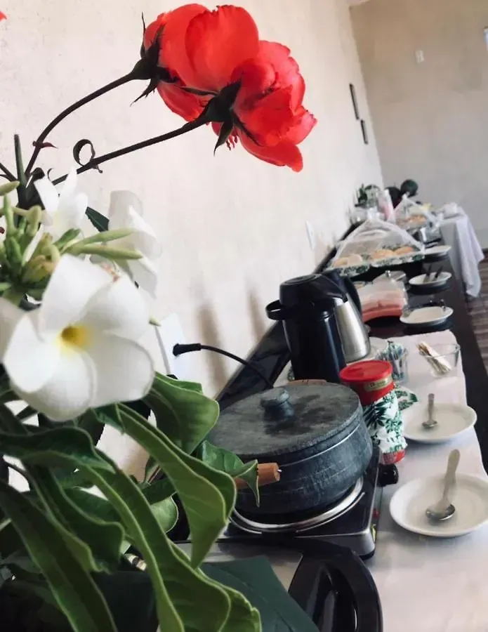 Uma mesa de bufê com uma flor vermelha em primeiro plano-Pousada-Morada-dos-Passaros