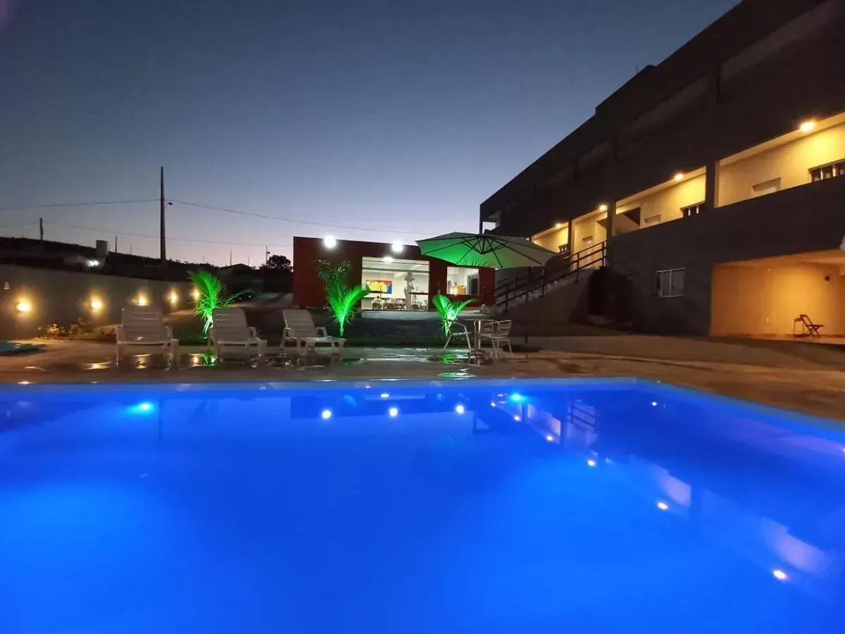 Uma grande piscina é iluminada à noite em frente a um prédio-Pousada-Morada-dos-Passaros