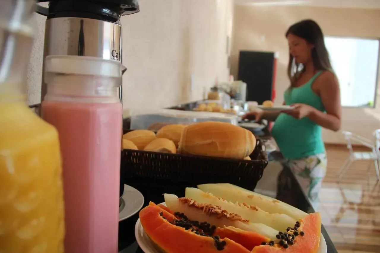 Uma mulher grávida está parada em frente a uma mesa cheia de comida e bebidas.-Pousada-Morada-dos-Passaros