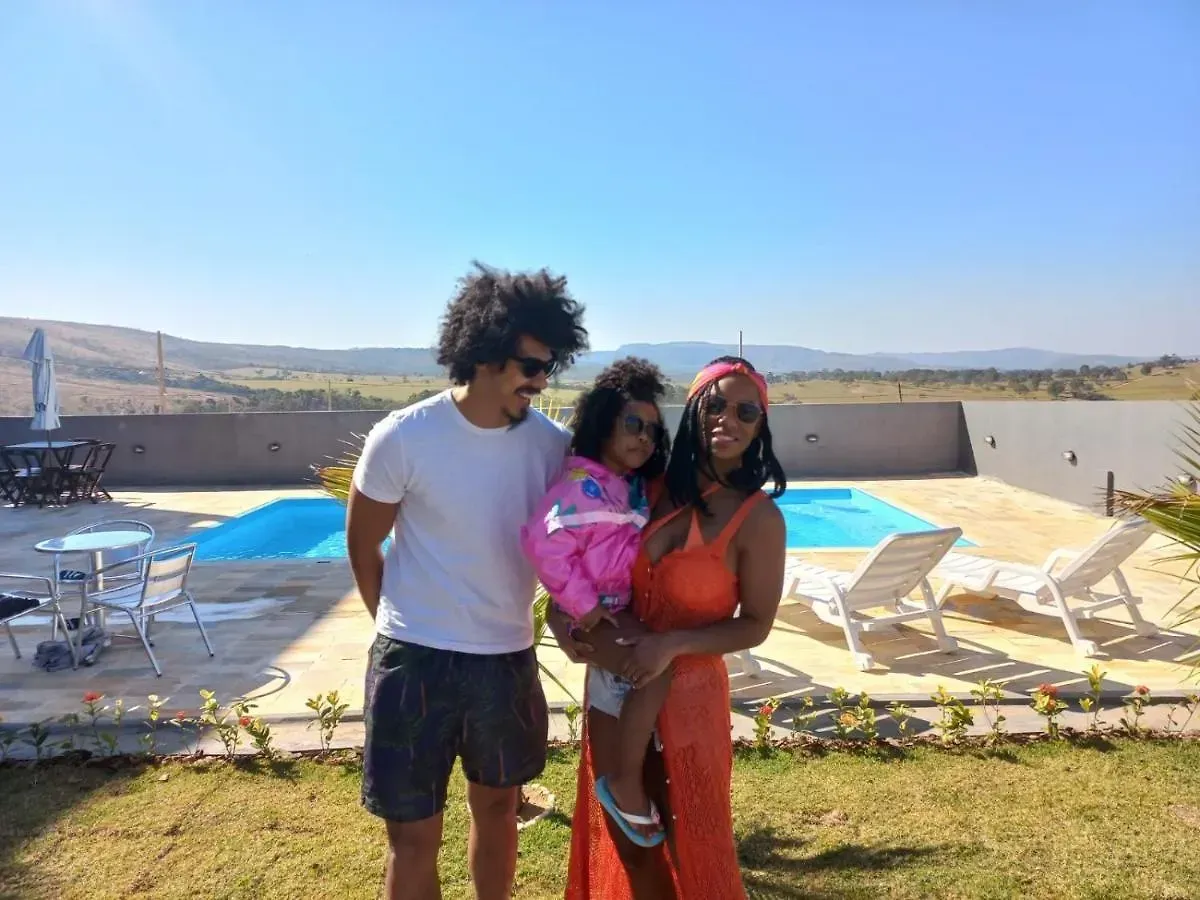 Um homem e uma mulher estão segurando um bebê em frente a uma piscina.-Pousada-Morada-dos-Passaros