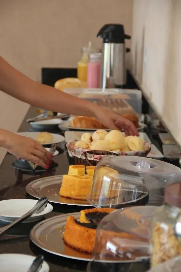 Uma pessoa está de pé em uma mesa com pratos de comida sobre ela.-Pousada-Morada-dos-Passaros