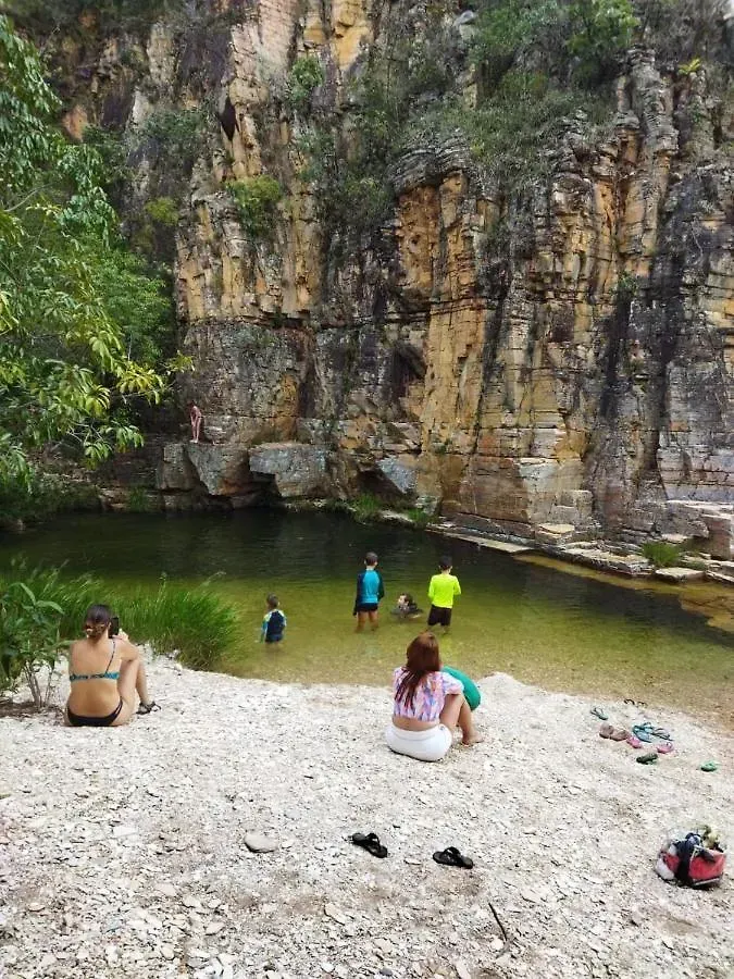 Um grupo de pessoas está sentado em uma praia rochosa perto de um rio.-Pousada-Morada-dos-Passaros