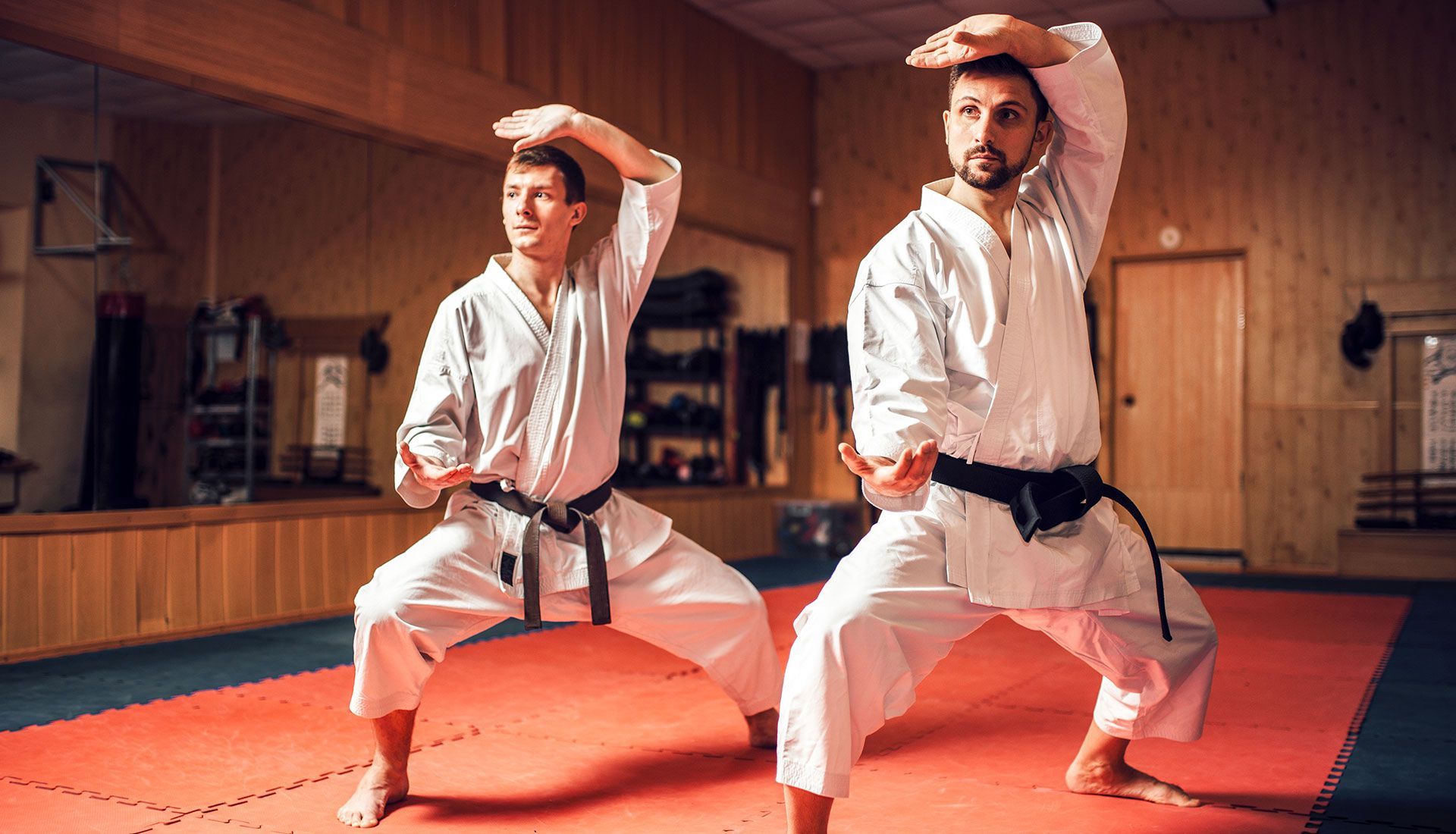 Two people in karate uniforms practicing a kata in a dojo.