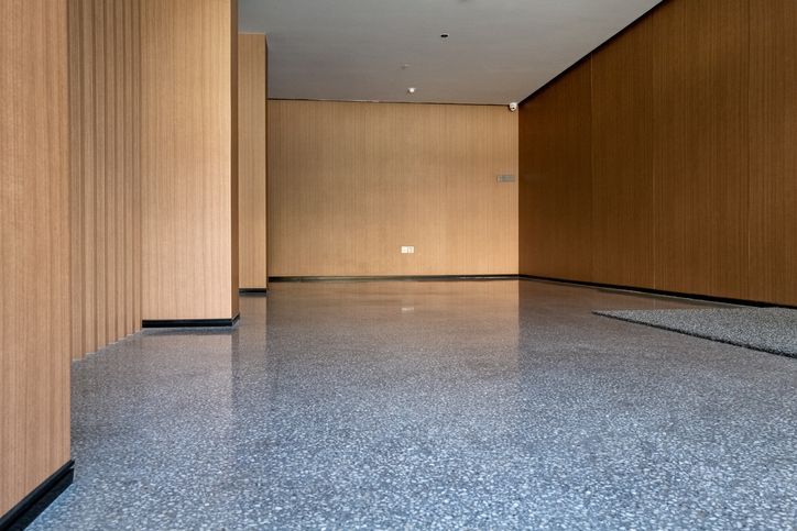 An empty room with a gray floor and wooden walls.