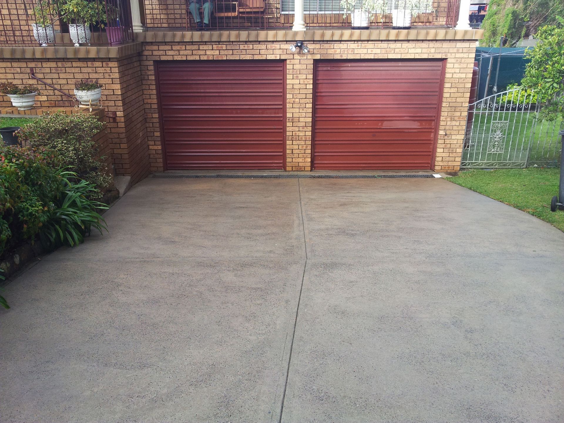 A Driveway With Two Red Garage Doors in Front of a Brick House — All Clean Pressure Cleaning in Valentine, NSW