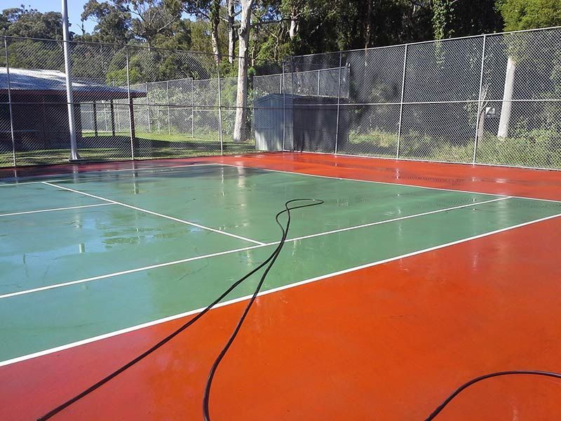 A Green and Red Tennis Court With a Fence in the Background — All Clean Pressure Cleaning in Valentine, NSW