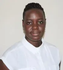 Woman with dark skin wearing a white shirt, smiling, in front of a light wall.