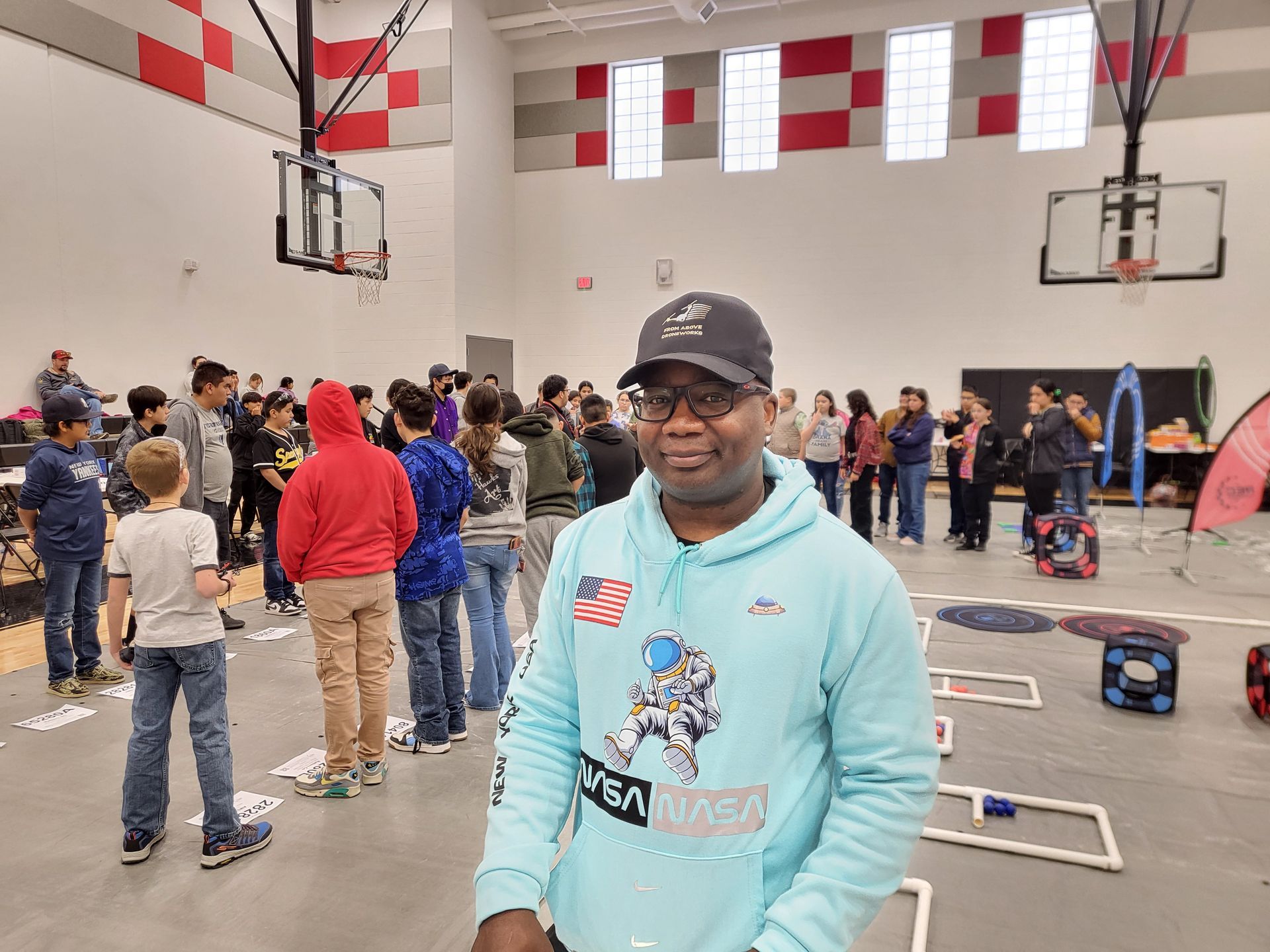 Owner of From Above Droneworks, wearing a blue hoodie, volunteers at an aerial drone competition at Hanks Middle School.