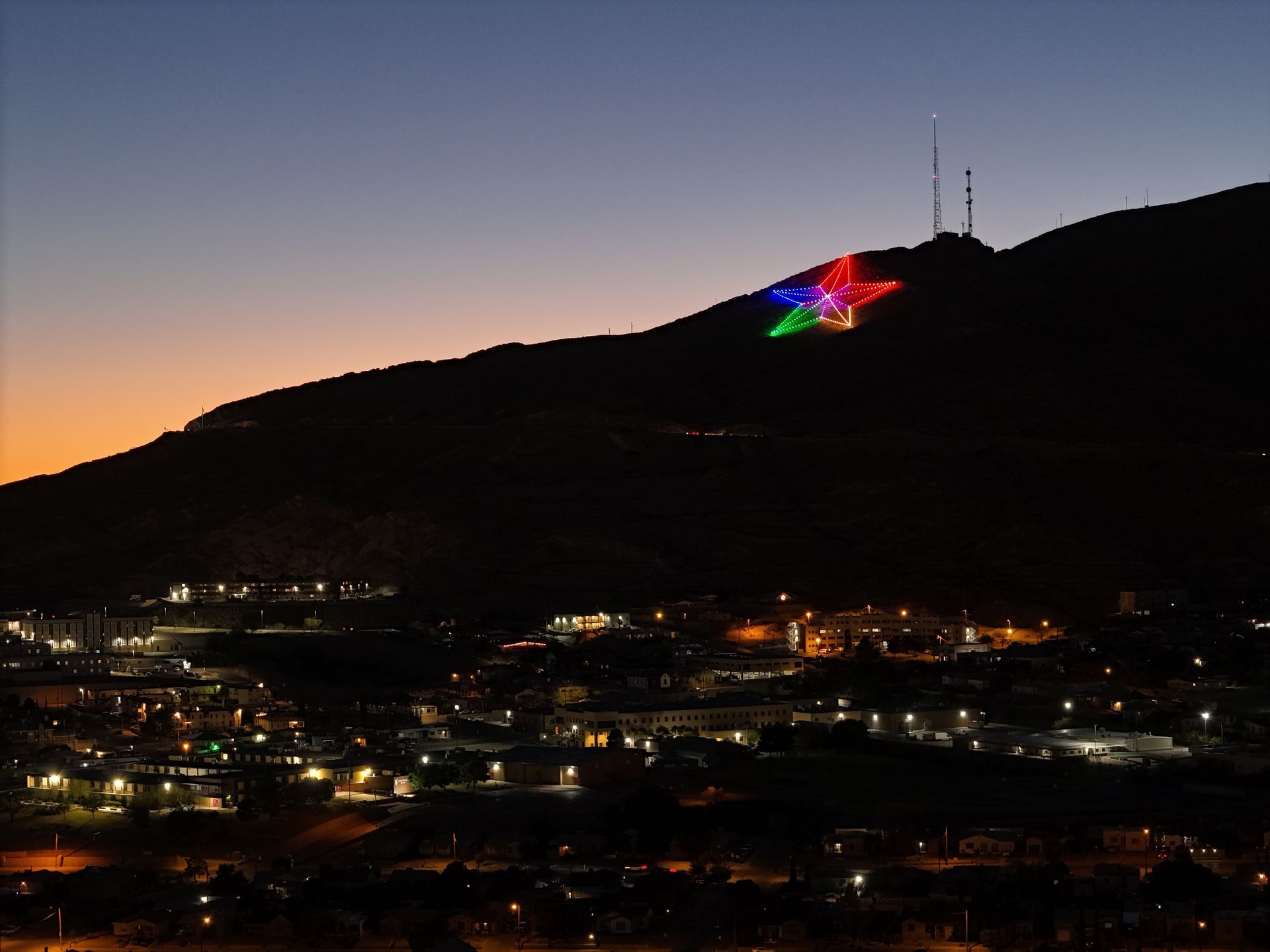 Aerial view of the Franklin Mountain Star in El Paso, Texas, illuminated at night.