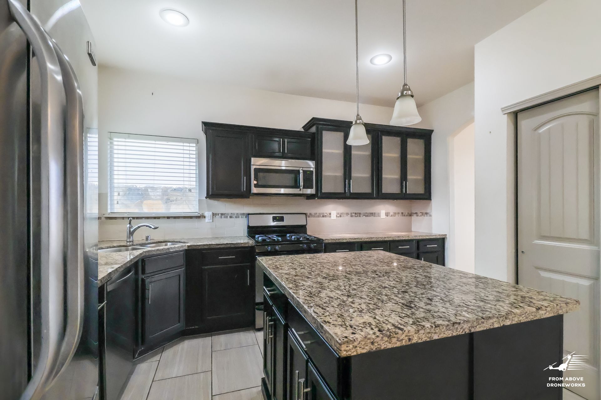 Indoor photo of a kitchen area featuring a central island with modern appliances and stylish decor.