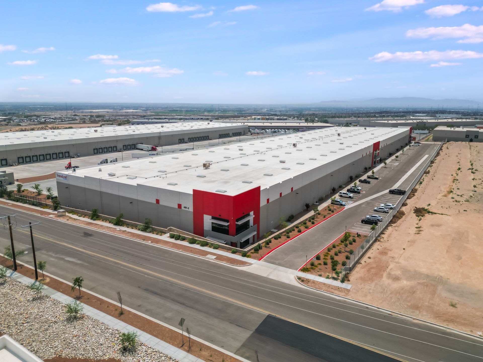 Aerial view of an industrial warehouse distribution center in El Paso, Texas, highlighting a large facility with multiple loading docks, trucks, and adjacent roadways. Key logistics hub in El Paso cityscape.