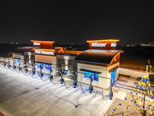 Night aerial view of Mister Car Wash Grand Opening event with illuminated property.