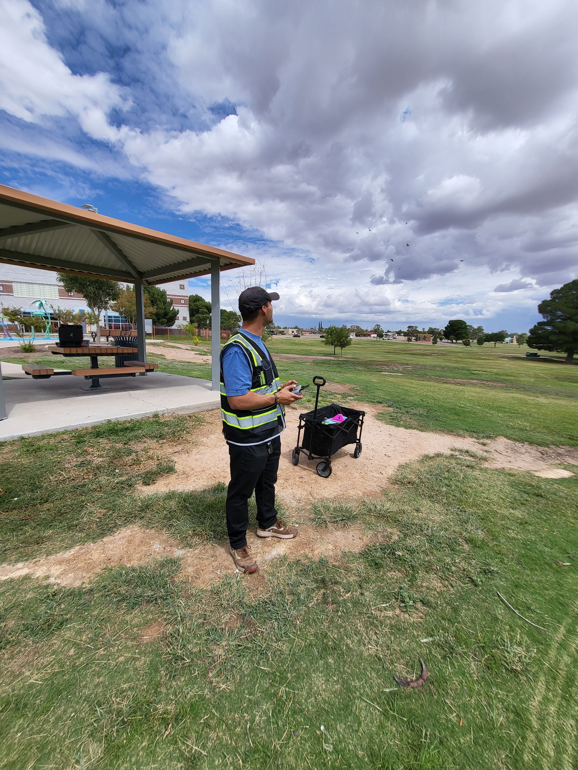 Drone operator wearing a reflective vest while flying a drone in a East El Paso Park