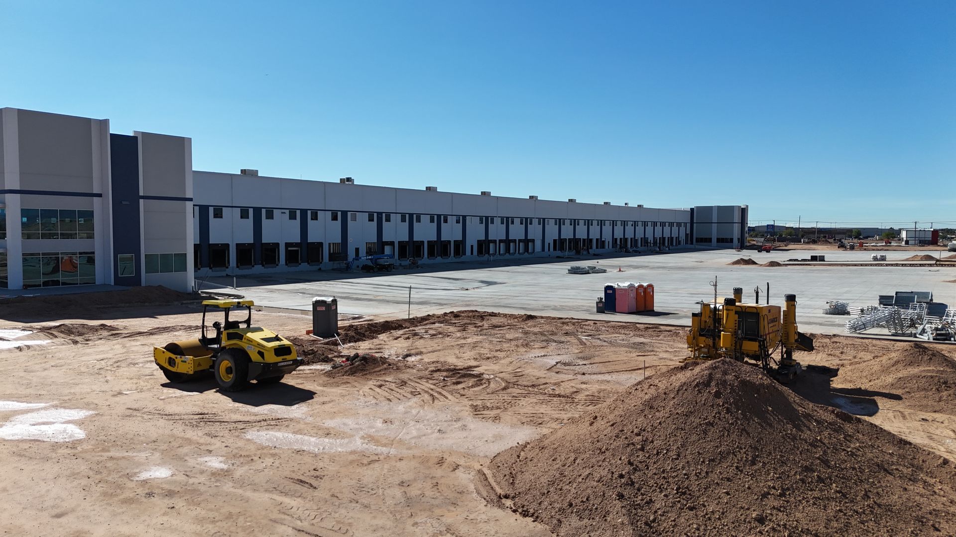 Ground-level drone image of an industrial warehouse construction site with heavy equipment in El Paso, Texas.