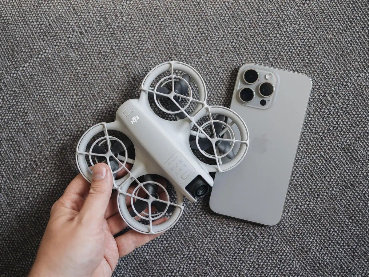 DJI Neo drone next to a smartphone, showcasing its compact size for easy portability.