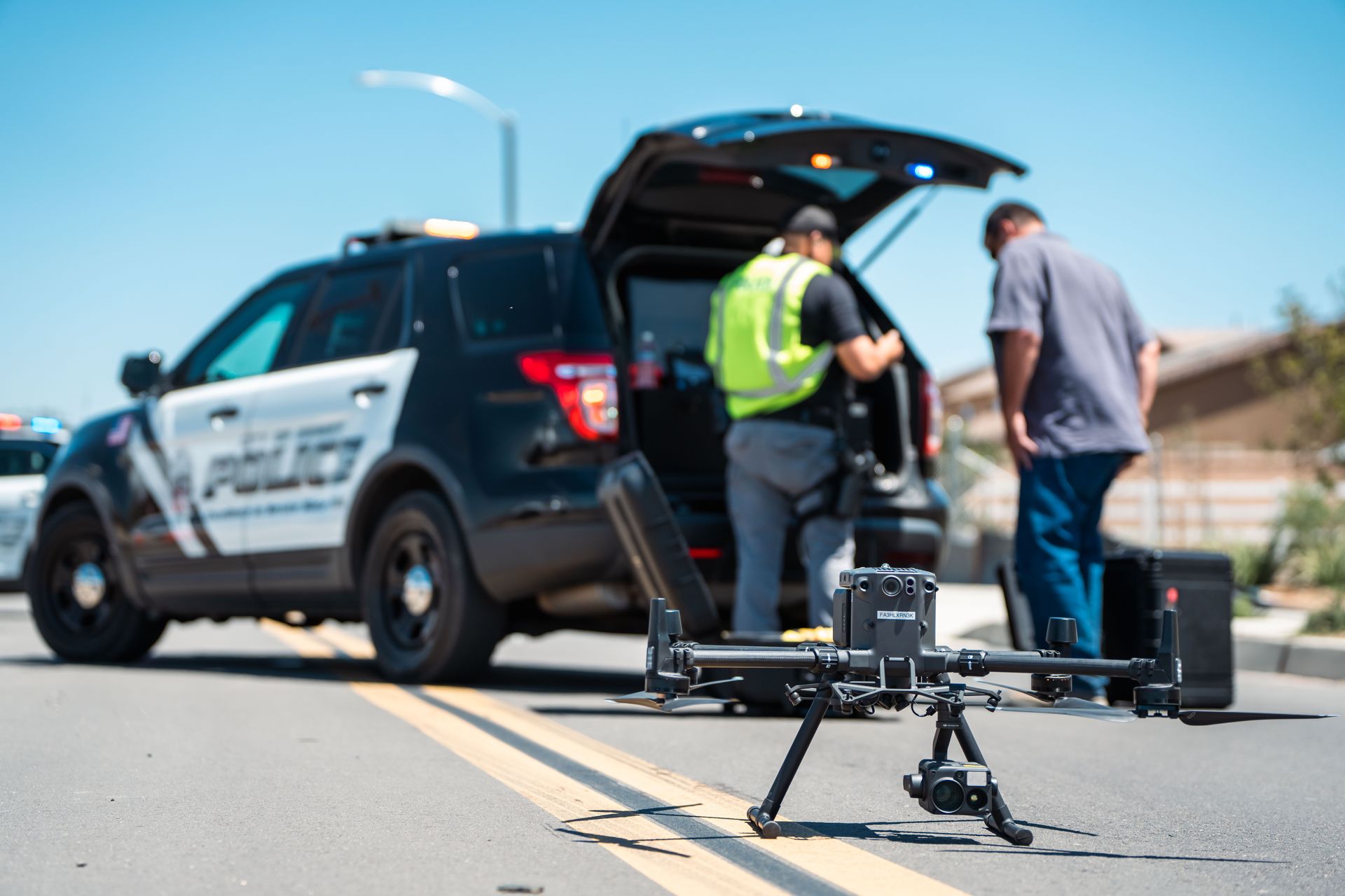 Police drone deployment scene with officers setting up UAV system from patrol vehicle