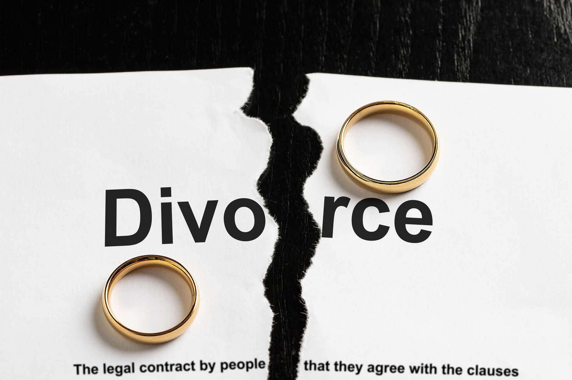 A closeup of a divorce document with two wedding rings symbolizing the end of a marriage A closeup of a divorce document with two wedding rings symbolizing the end of a marriage
