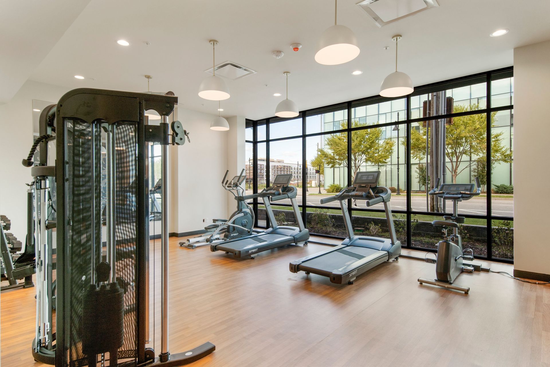 Gym with exercise equipment and large windows overlooking a green outdoor space.