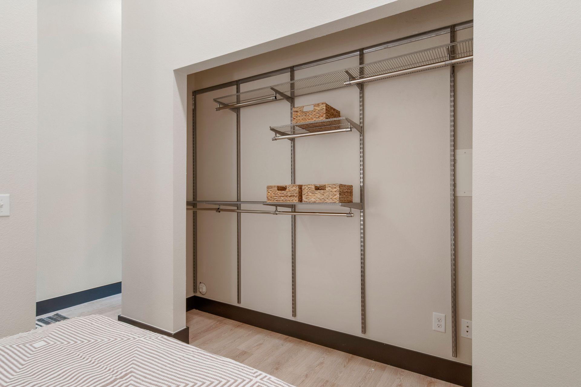 Empty closet with metal shelving and baskets on shelves. Light-colored walls and floor.