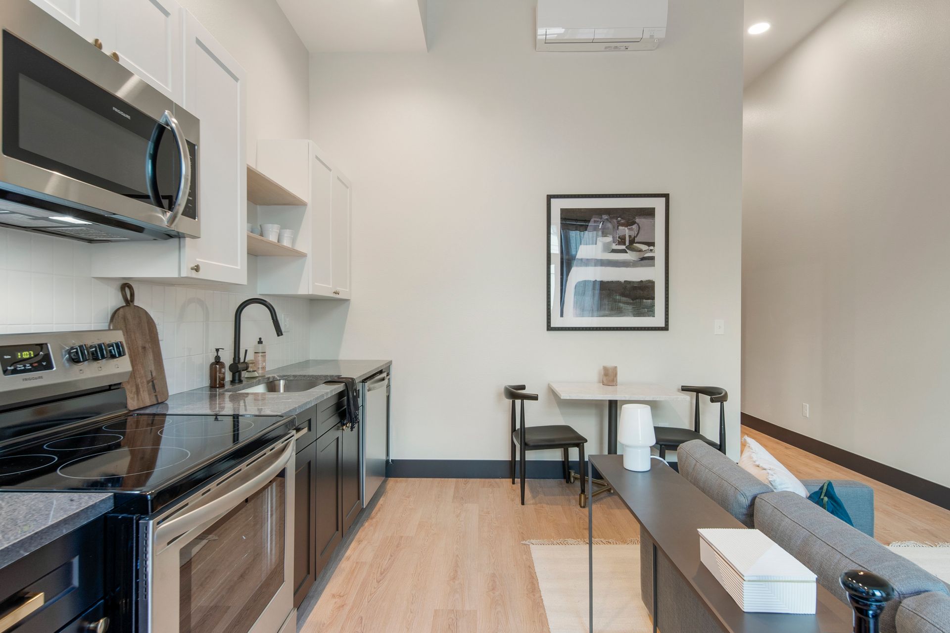 Modern kitchen with stainless steel appliances, dark countertops, and a small dining area.